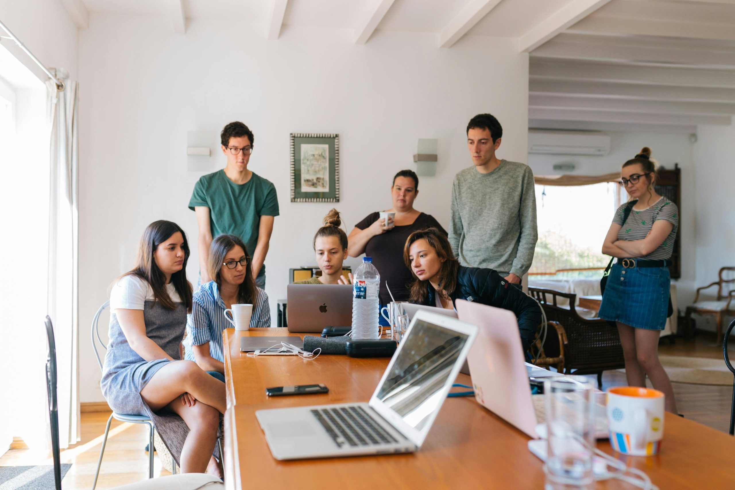 Equipo reunido colaborando con varios ordenadores portátiles
