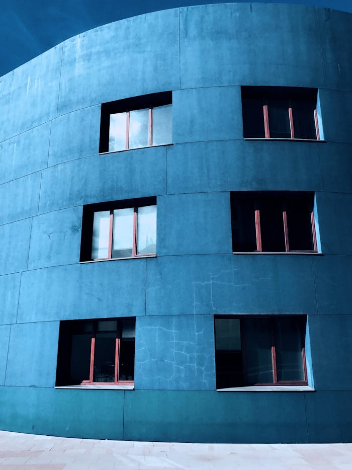 A striking blue modern building facade with minimalist architecture, featuring large windows.
